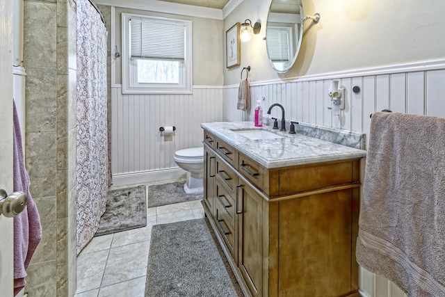 full bath featuring tile patterned floors, a wainscoted wall, toilet, vanity, and ornamental molding