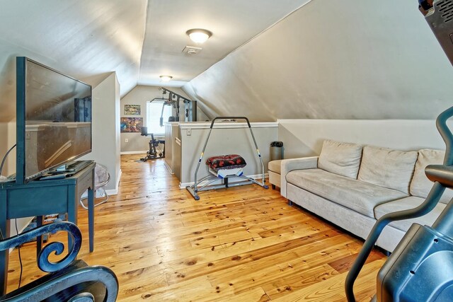 interior space featuring hardwood / wood-style floors, lofted ceiling, and baseboards