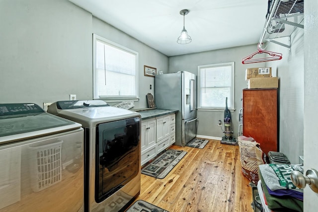 laundry room featuring light wood-type flooring, washer and dryer, and cabinet space