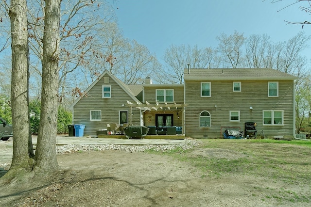 back of property with a pergola, a wooden deck, and a chimney