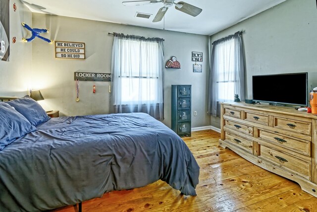 bedroom with baseboards, visible vents, a ceiling fan, and light wood-style floors
