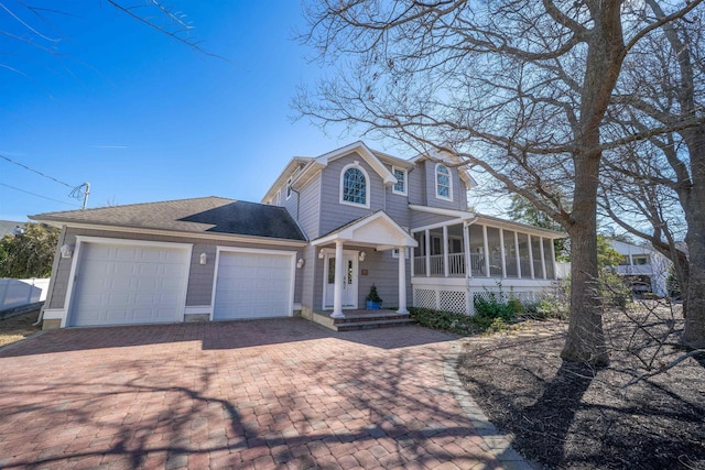 view of front of property with a garage, a sunroom, decorative driveway, and roof with shingles