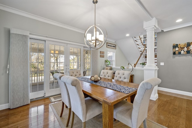 dining space with crown molding, decorative columns, baseboards, and hardwood / wood-style flooring