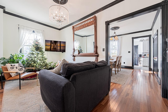 living room with wood-type flooring, crown molding, and a notable chandelier