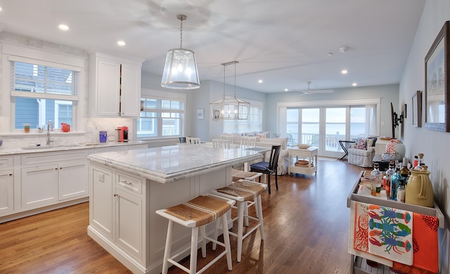 885 21st St W, Unit West, Avalon, NJ 08202 - kitchen with open floor plan, a kitchen island, a kitchen breakfast bar, white cabinets, and light stone counters