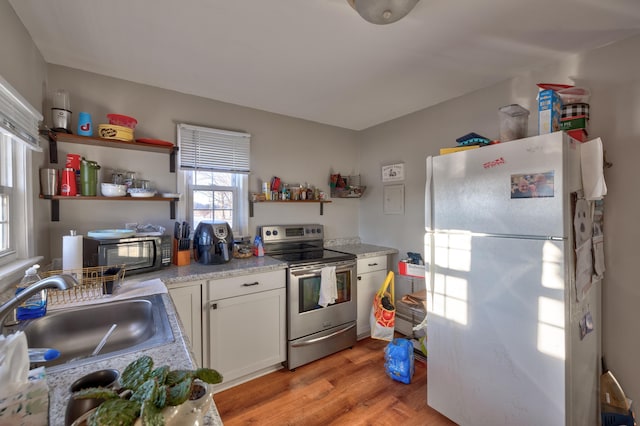 103 Bate Ave, Lower Township, NJ 08204 - kitchen with white cabinets, light wood-type flooring, white refrigerator, sink, and stainless steel range with electric cooktop
