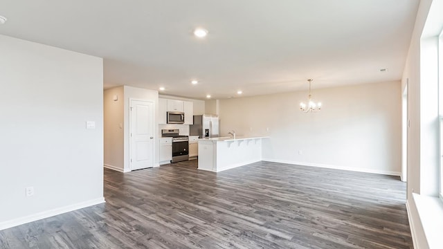 unfurnished living room with dark hardwood / wood-style flooring, a chandelier, and sink