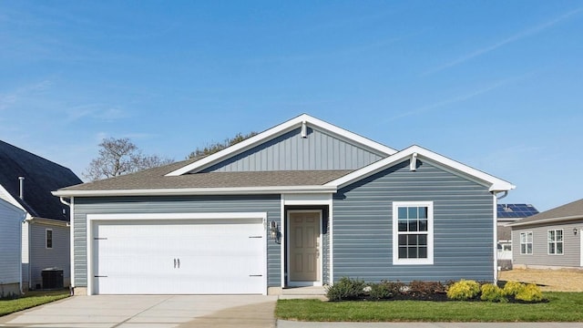 ranch-style home with central AC unit, a garage, board and batten siding, driveway, and roof with shingles