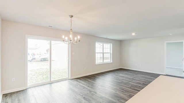 unfurnished dining area with a notable chandelier and dark wood-type flooring