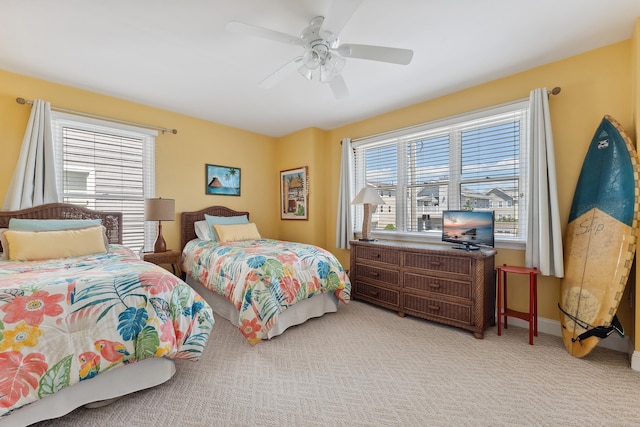 bedroom featuring multiple windows, ceiling fan, light carpet, and baseboards