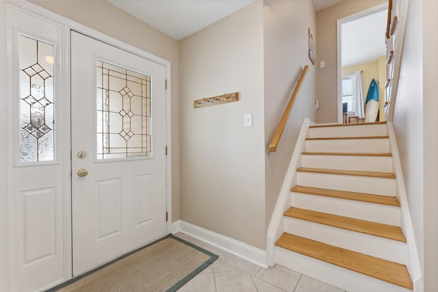 entrance foyer with light tile patterned floors, stairway, and baseboards