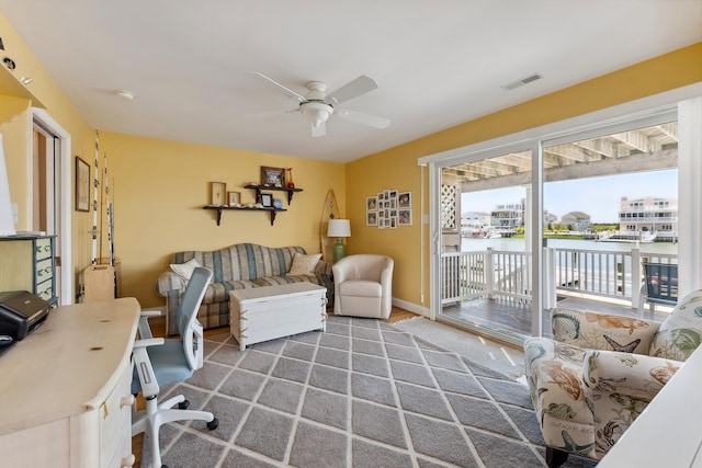 office space featuring a water view, ceiling fan, visible vents, and baseboards