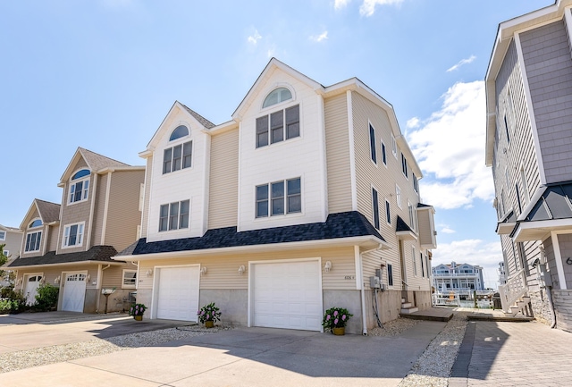 townhome / multi-family property featuring a garage, roof with shingles, and driveway