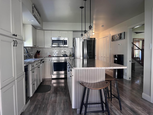 407 Elmwood Ave, Marmora, NJ 08223 - kitchen featuring hanging light fixtures, tasteful backsplash, white cabinets, a kitchen island, and appliances with stainless steel finishes