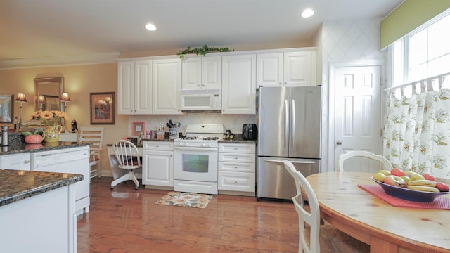 kitchen with dark hardwood / wood-style flooring, white appliances, white cabinetry, and dark stone countertops