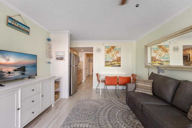 living room with ornamental molding, a textured ceiling, and light wood-type flooring