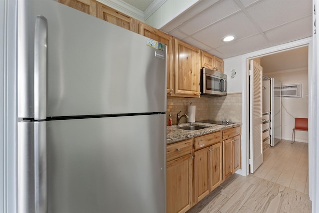 kitchen with appliances with stainless steel finishes, a paneled ceiling, sink, decorative backsplash, and light stone countertops