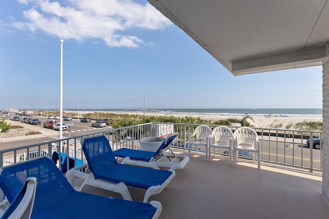 balcony with a water view and a view of the beach