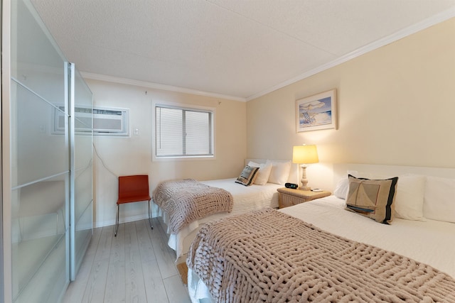 bedroom featuring a wall mounted air conditioner, hardwood / wood-style flooring, ornamental molding, and a textured ceiling