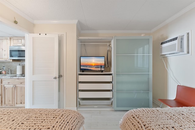 bedroom featuring crown molding, a textured ceiling, light hardwood / wood-style flooring, and an AC wall unit