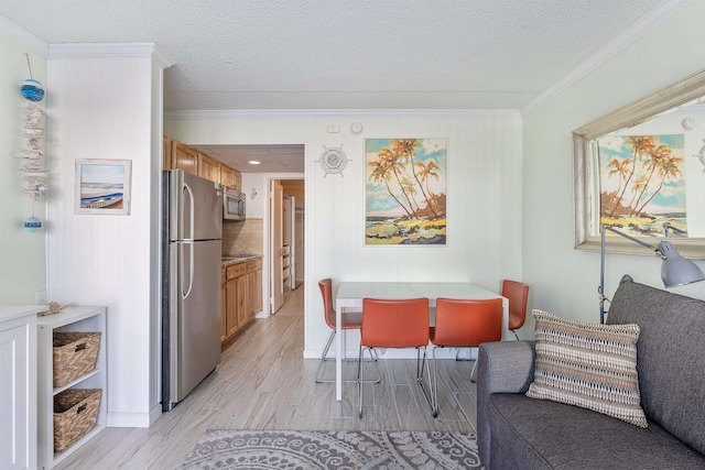 dining area featuring light hardwood / wood-style flooring, ornamental molding, and a textured ceiling