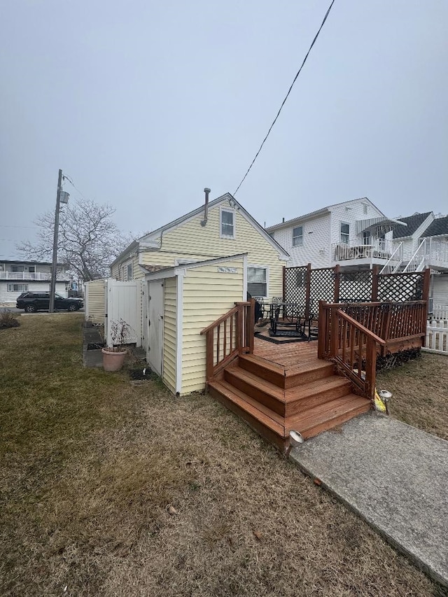 back of property featuring a yard, fence, and a wooden deck