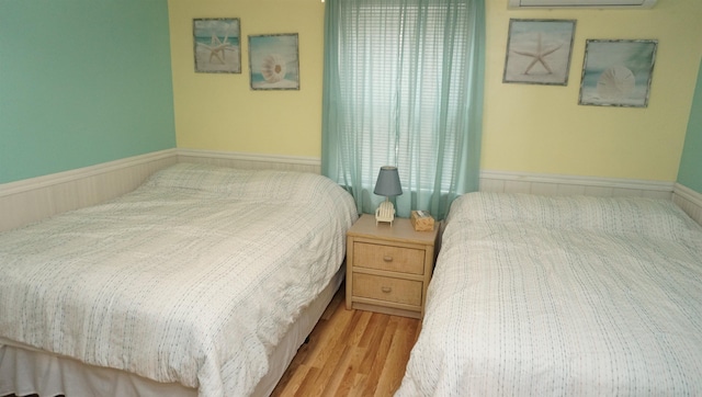 bedroom with a wall mounted air conditioner and light wood-type flooring