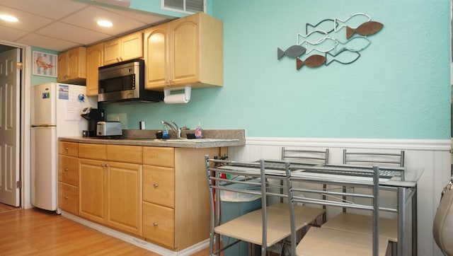 kitchen with white fridge, light hardwood / wood-style floors, and light brown cabinets