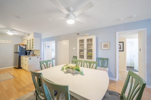 dining space with light hardwood / wood-style floors and ceiling fan