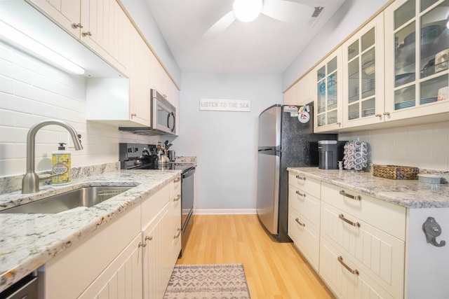 kitchen featuring decorative backsplash, appliances with stainless steel finishes, ceiling fan, sink, and light hardwood / wood-style floors