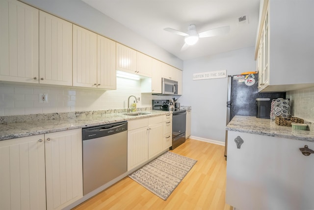 kitchen with light stone countertops, ceiling fan, sink, light hardwood / wood-style flooring, and appliances with stainless steel finishes