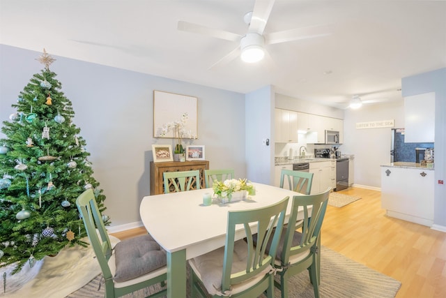 dining room featuring light wood-type flooring, ceiling fan, and sink