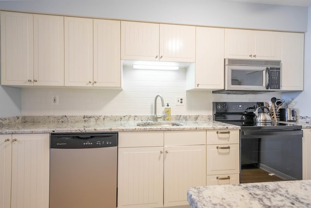 kitchen with light stone countertops, appliances with stainless steel finishes, tasteful backsplash, and sink