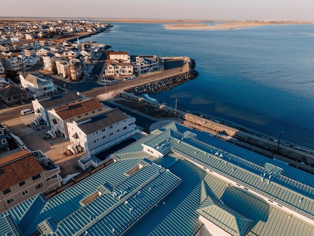 aerial view at dusk featuring a water view and a beach view