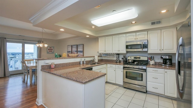 kitchen featuring sink, appliances with stainless steel finishes, white cabinetry, a raised ceiling, and kitchen peninsula