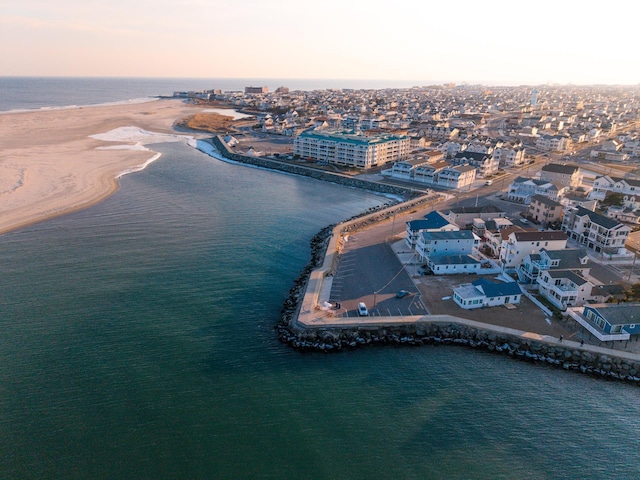 aerial view at dusk featuring a water view and a beach view