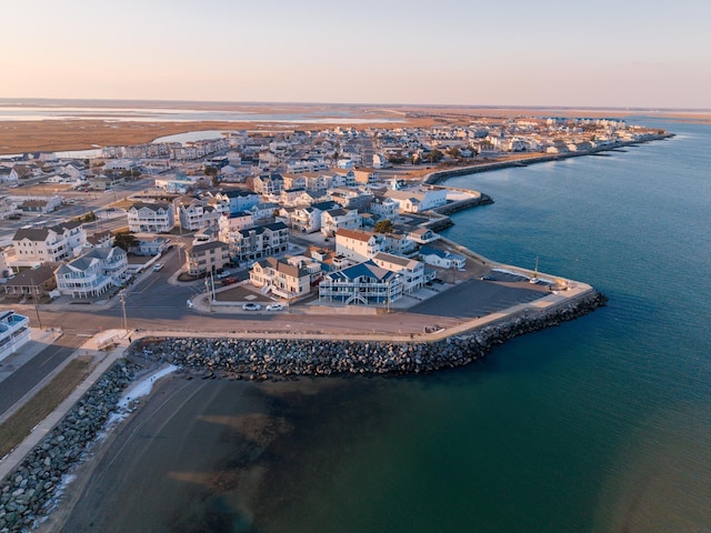 aerial view at dusk with a water view and a beach view