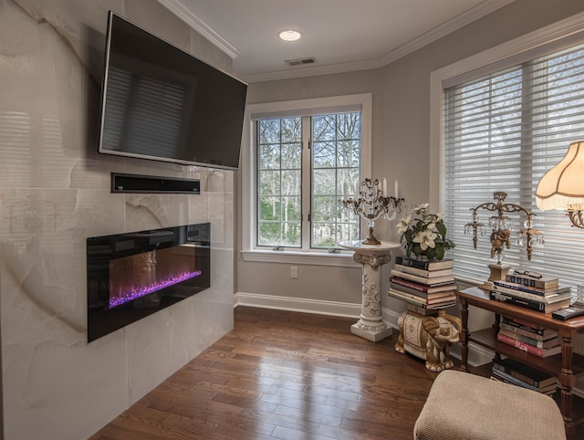 sitting room with a tiled fireplace, crown molding, and dark hardwood / wood-style flooring