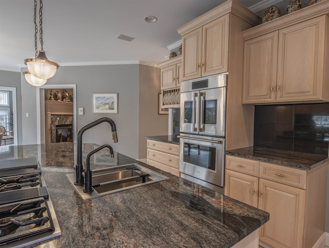 kitchen featuring sink, light brown cabinets, stainless steel double oven, a premium fireplace, and decorative light fixtures