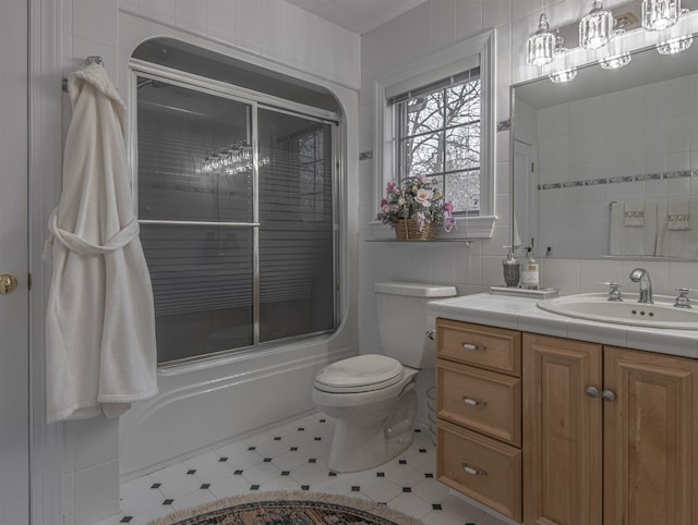 full bathroom featuring vanity, toilet, enclosed tub / shower combo, and tile walls