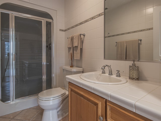 bathroom featuring tile patterned flooring, vanity, toilet, and a shower with shower door