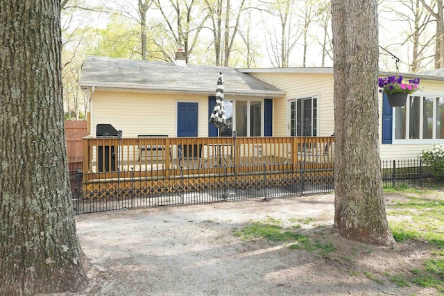 back of property featuring a wooden deck, a chimney, and fence