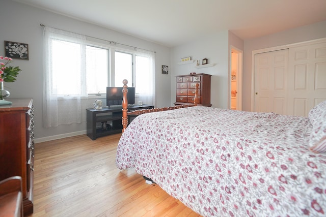 bedroom with light wood finished floors, a closet, and baseboards
