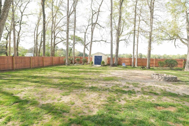 view of yard with a fenced backyard, an outdoor fire pit, an outdoor structure, and a shed