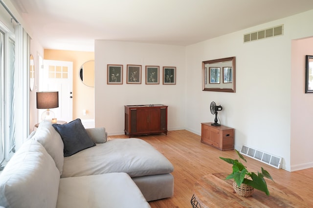 living room featuring light wood finished floors, visible vents, and baseboards