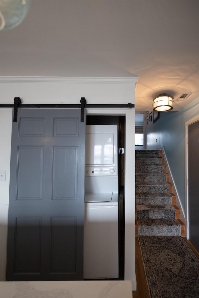 stairs with a barn door and stacked washer / drying machine