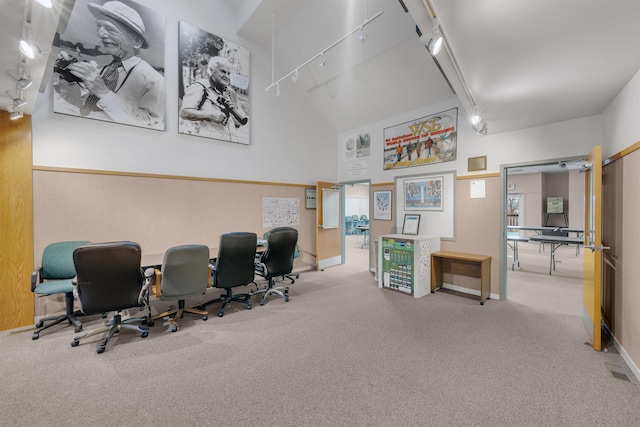 office space with a towering ceiling, light carpet, and track lighting