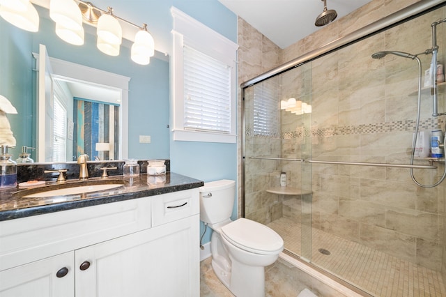 bathroom with a shower with door, vanity, and toilet