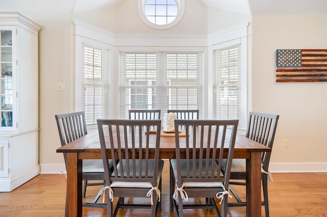 dining area with light wood-type flooring and vaulted ceiling