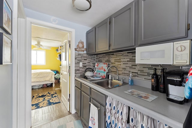 kitchen with tasteful backsplash, ceiling fan, gray cabinetry, and sink